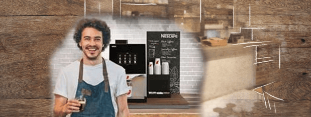 Barista sonriente frente a máquinas NESCAFÉ® e insumos.