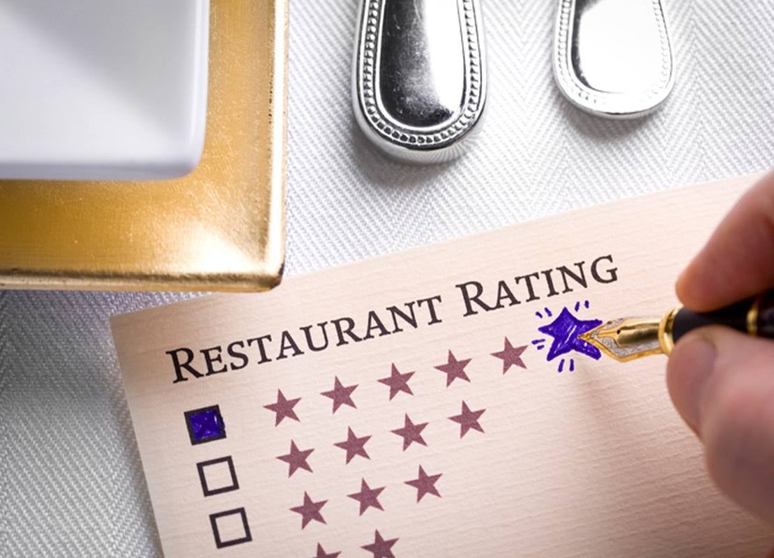 Persona calificando con cinco estrellas un restaurante en una tarjeta de evaluación.