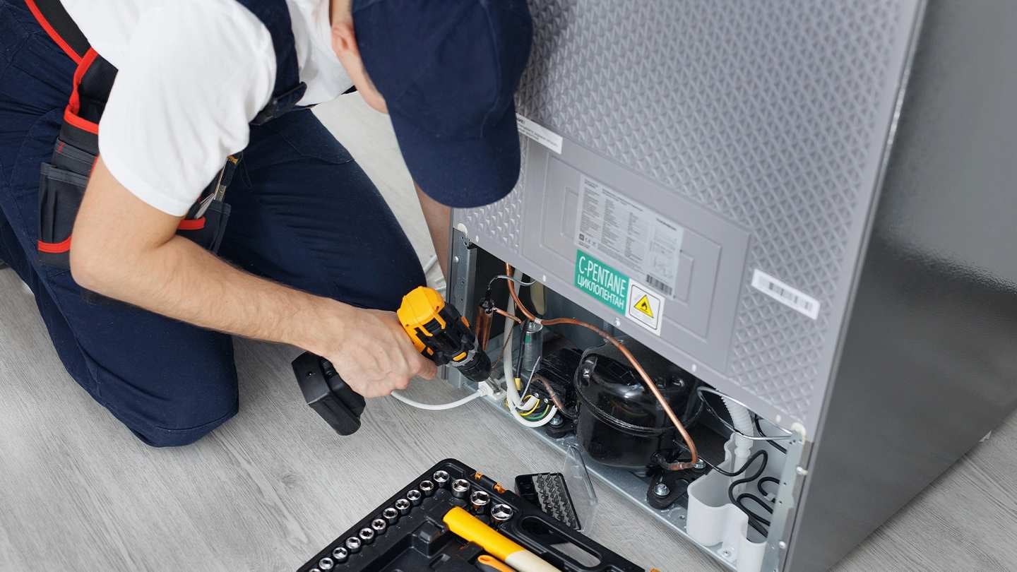 Técnico realiza mantenimiento de equipos de cocina en un sistema de refrigeración profesional.