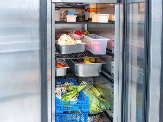 Refrigerador con alimentos organizados para conservar propiedades organolépticas en cocina profesional.