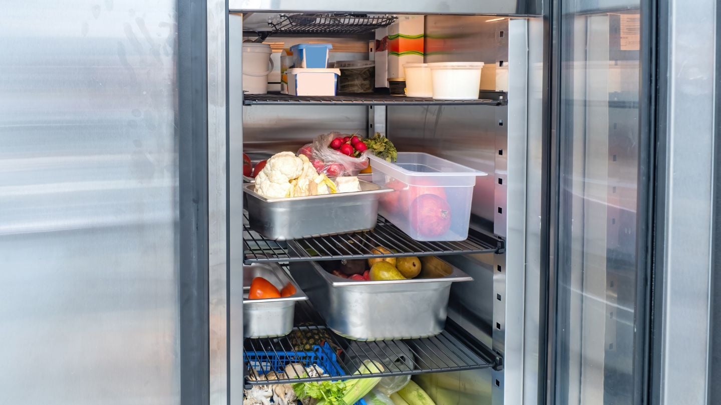Refrigerador con alimentos organizados para conservar propiedades organolépticas en cocina profesional.
