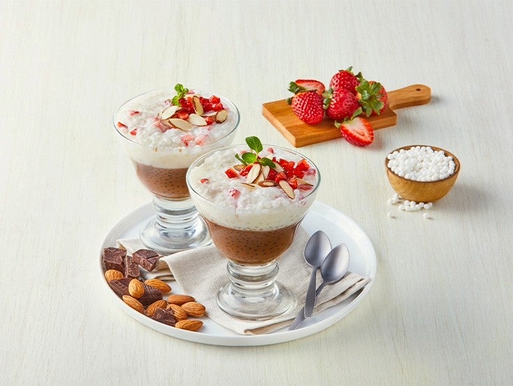Postres helados en copas con crema de chocolate, almendras y fresas sobre plato blanco