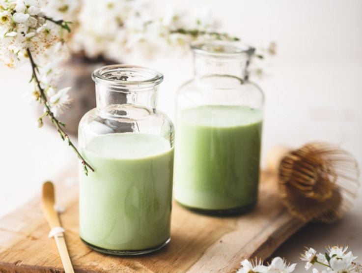 Botellas de cristal de té matcha elaborado con bebida vegetal sobre una tabla