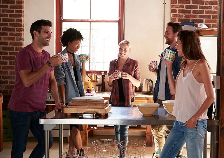 Grupo de personas conversando y tomando bebidas calientes en un espacio de cocina