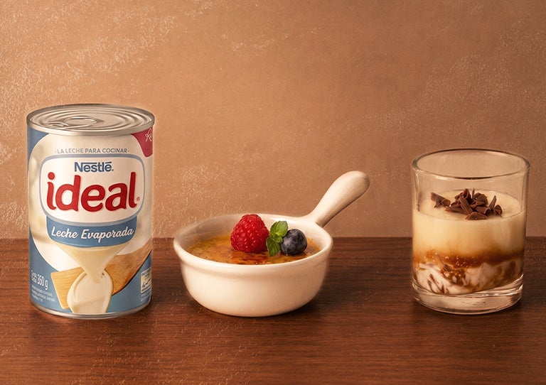 Lata de Leche Evaporada NESTLÉ® IDEAL® con postres cremosos sobre una mesa