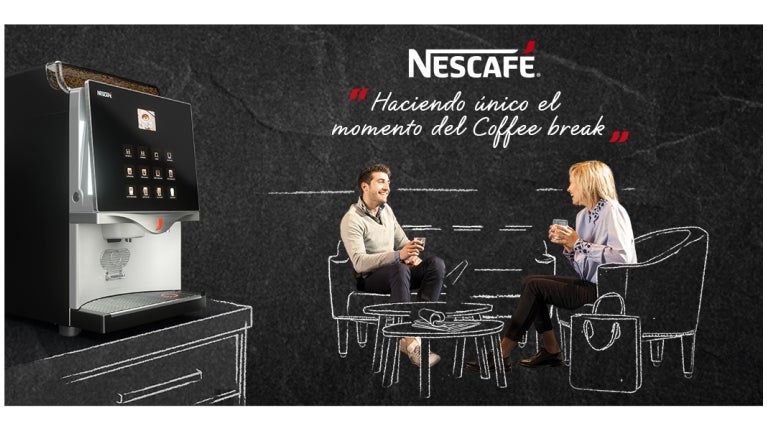 Colaboradores sentados conversando con una taza nescafé en mano y máquina al costado