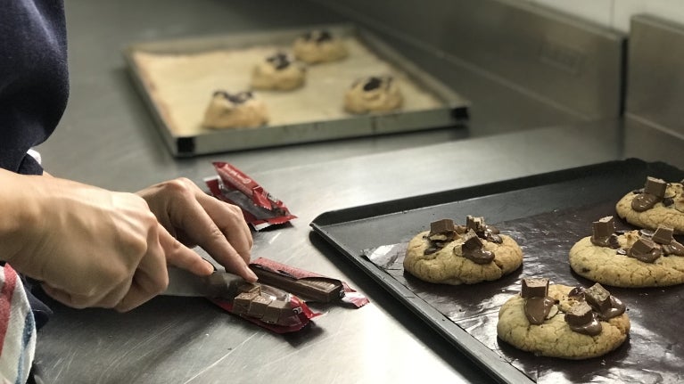 Manos cortando barras de chocolate kitkat para decorar galletas