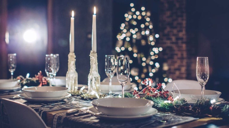 Cena navideña con copas de vino, velas y árbol