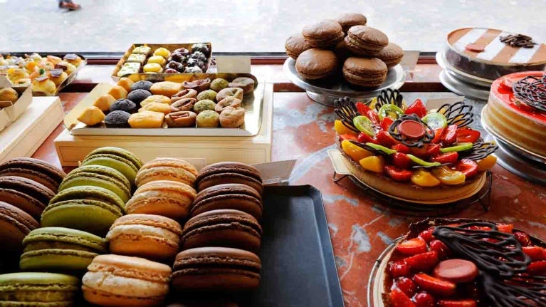 Mesa de postres con diferentes opciones como tartas, galletas, fruta, donas, entre otros