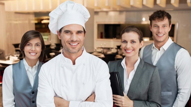 Dos camareros, una gerente de restaurante y un chef que recibieron capacitación de personal para tener un equipo eficiente