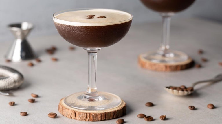 Cócteles sin alcohol como dos Martini Espresso sobre un portavasos de madera, decorados con granos de café