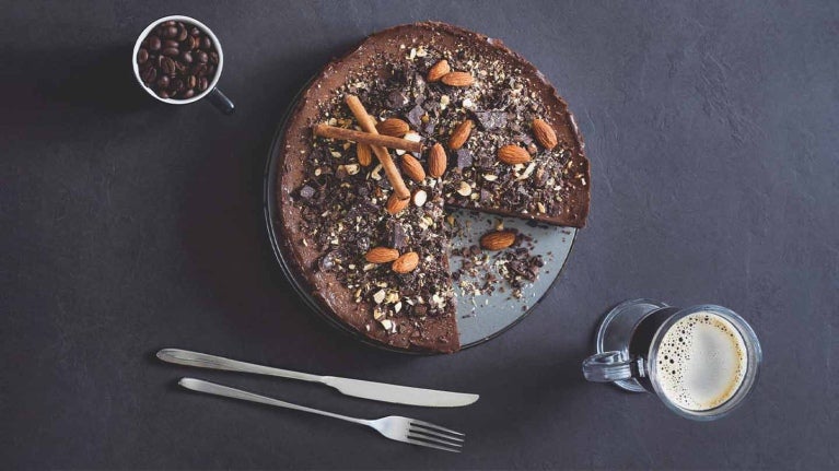 Vista superior de tarta de mousse de chocolate con almendras y café sobre fondo de pizarra que hacen un maridaje perfecto