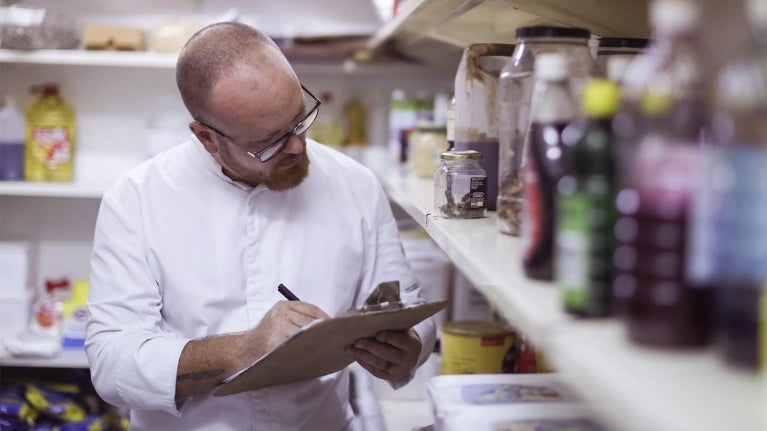 Chef ejecutivo en el almacén de un restaurante revisa y hace inventario de los ingredientes e insumos