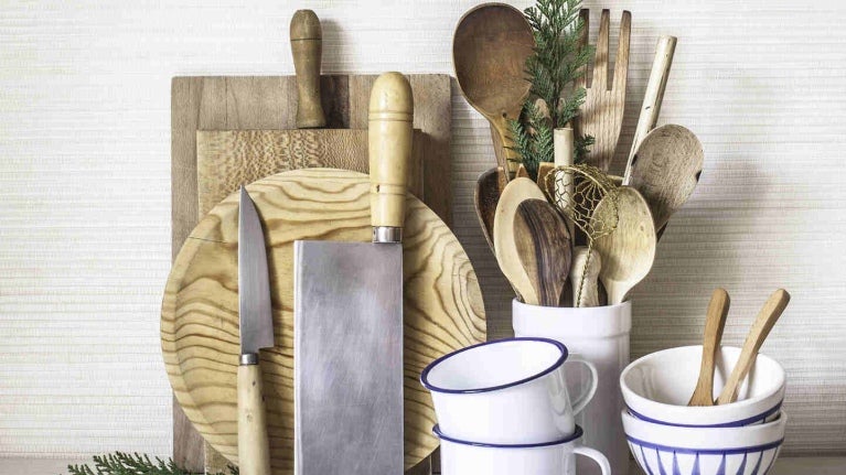 Utensilios de cocina en madera como diversas tablas de picar, cuchillos, cucharas, mezcladores, espátulas, tazas y pocillos