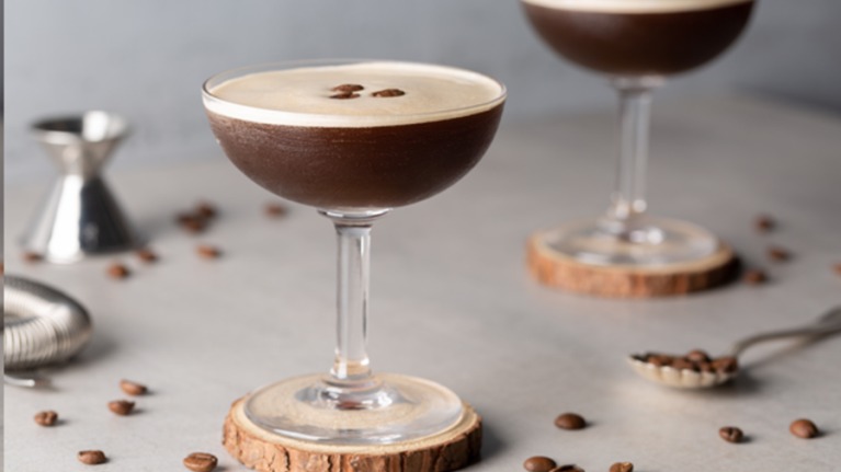 Cócteles sin alcohol como dos Martini Espresso sobre un portavasos de madera, decorados con granos de café