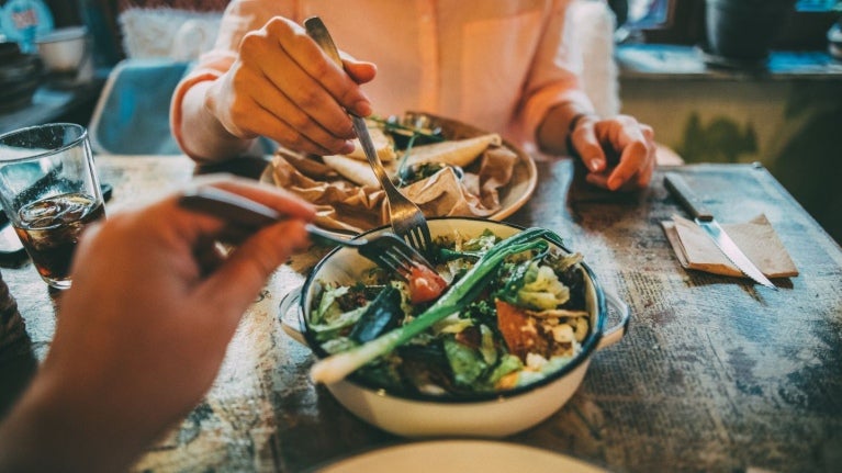 Dos personas disfrutan de ensaladas compuestas y frescas, y bebidas en un restaurante acogedor