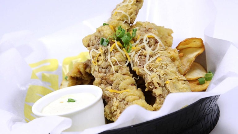 Un canasto con tiras de pollo empanizadas y salsa dip, ideal para un menú fácil y rápido.