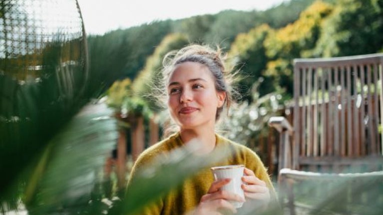 Persona disfrutando una degustación de café en un espacio al aire libre de un negocio gastronómico.