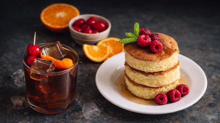 Café frío con cítricos, pancakes con frambuesas y frutas frescas propuesta de menú de temporada