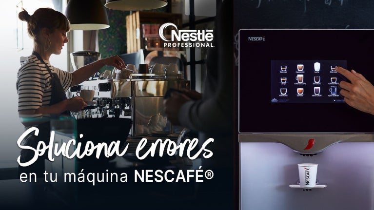 Barista opera una máquina de café, al lado la pantalla de un equipo automático en una cafetería.