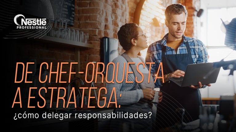 Dos personas revisan una tablet en cocina profesional con el texto sobre delegar responsabilidades