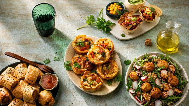 Plato con tartaletas saladas decoradas con hierbas y acompañamientos sobre mesa
