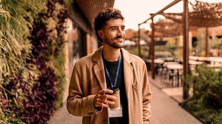 Hombre sosteniendo un vaso de café en el exterior de una oficina