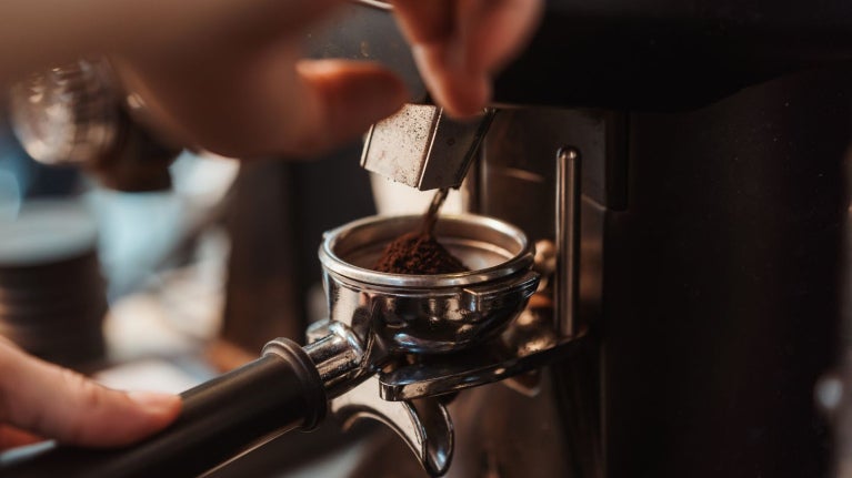 Persona coloca café molido en el portafiltro de una máquina de espresso