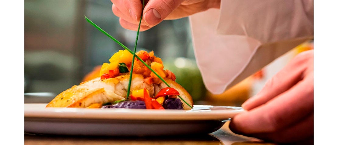 Chef decorando el plato fuerte de una cena romántica