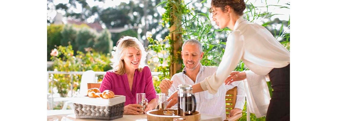 Mesera atendiendo a una pareja en un restaurante al aire libre