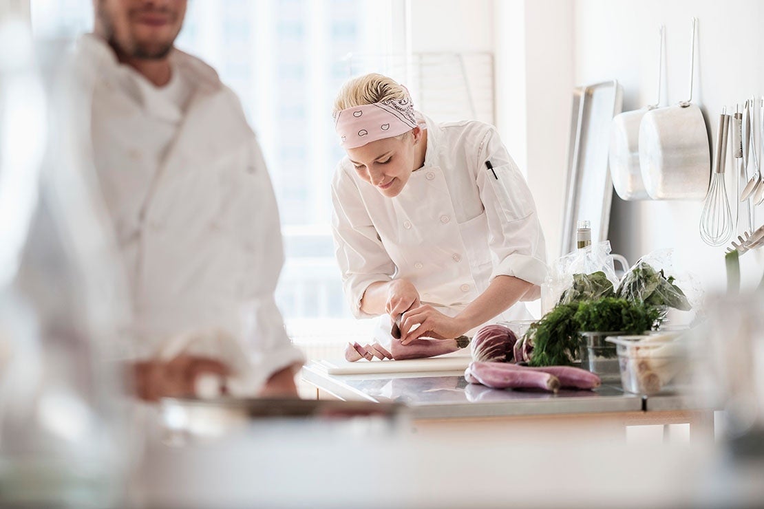 Mujer elaborando platos en una cocina profesional