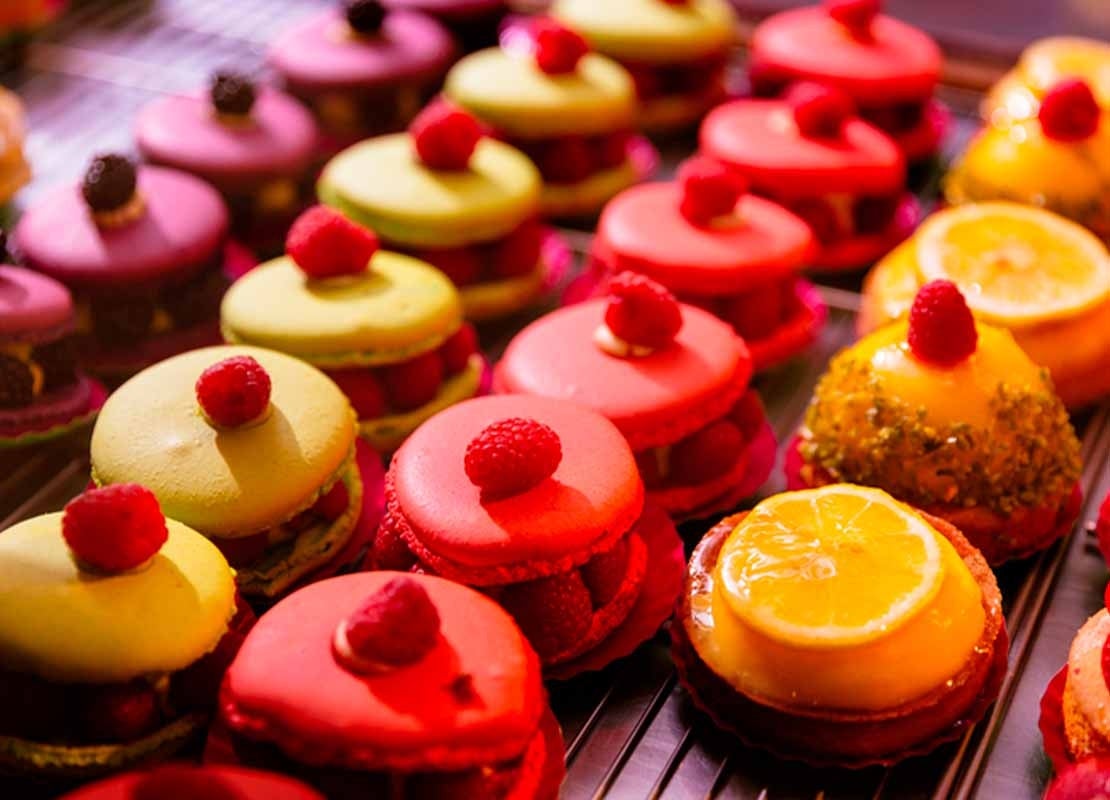 Preparaciones dulces multicolores con frambuesas frescas puestas sobre una mesa de postres de madera