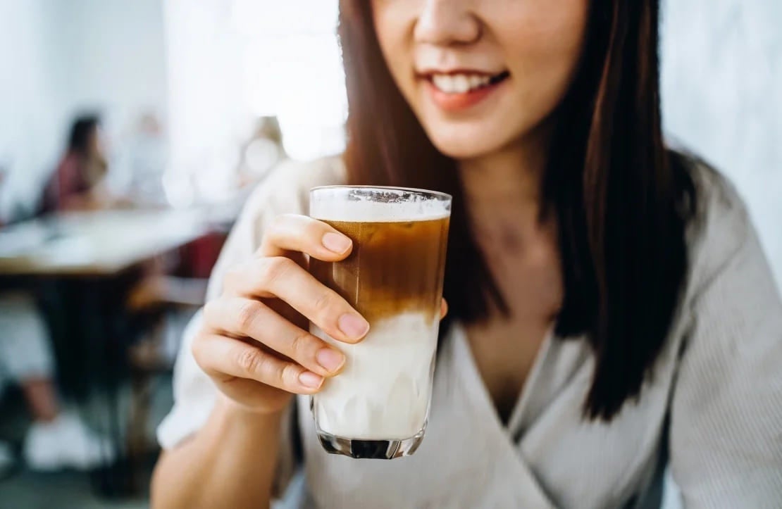 Mujer tomando una bebida de café hecha por baristas