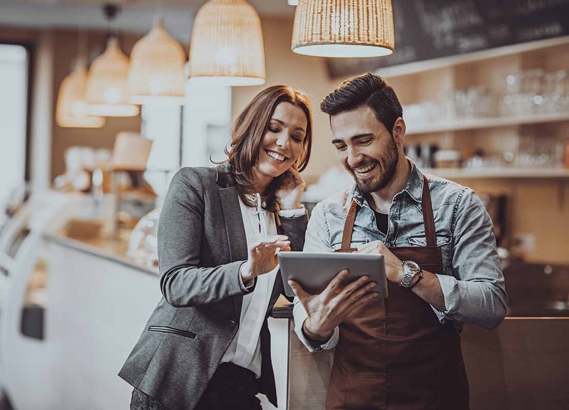 Chef escribe un menú de restaurante sobre una pizarra frente a su negocio que es espacioso y colorido