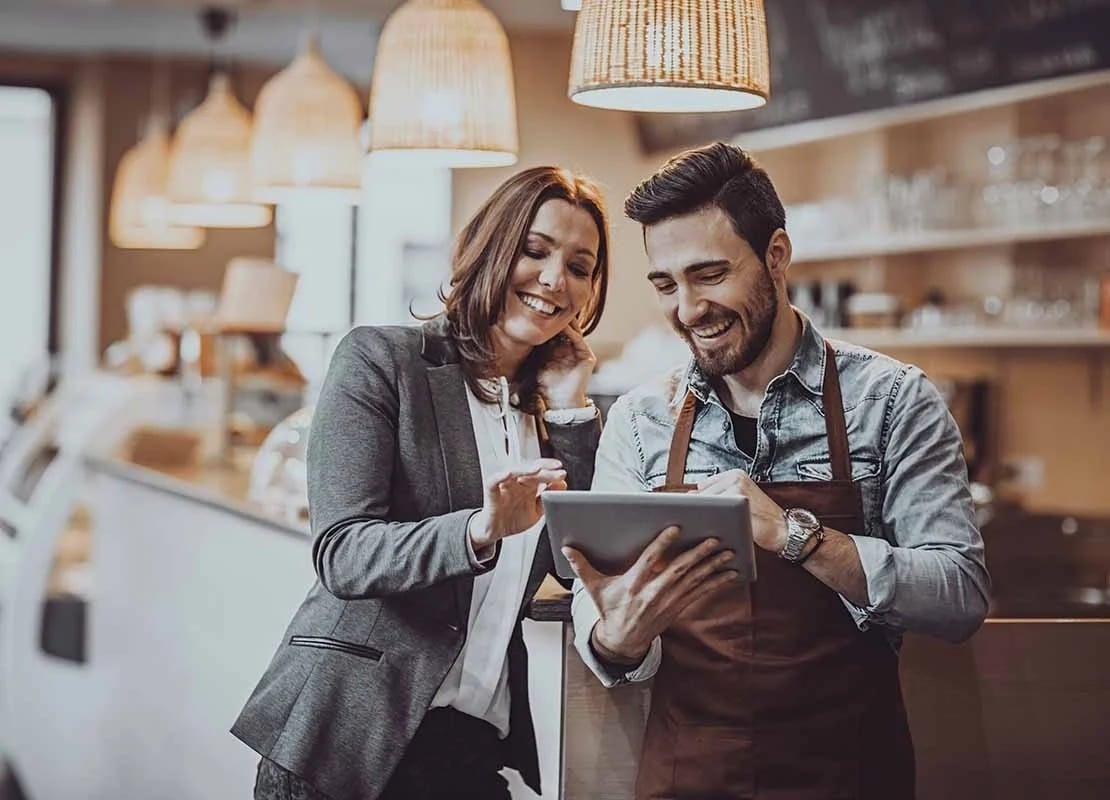 Gerente y barista eligen los platos y diseñan el menú de restaurante desde una Tablet frente al mostrador de su negocio