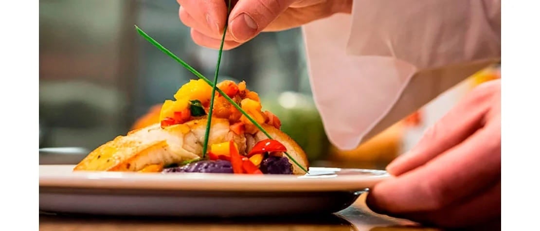 Chef decorando el plato fuerte de una cena romántica