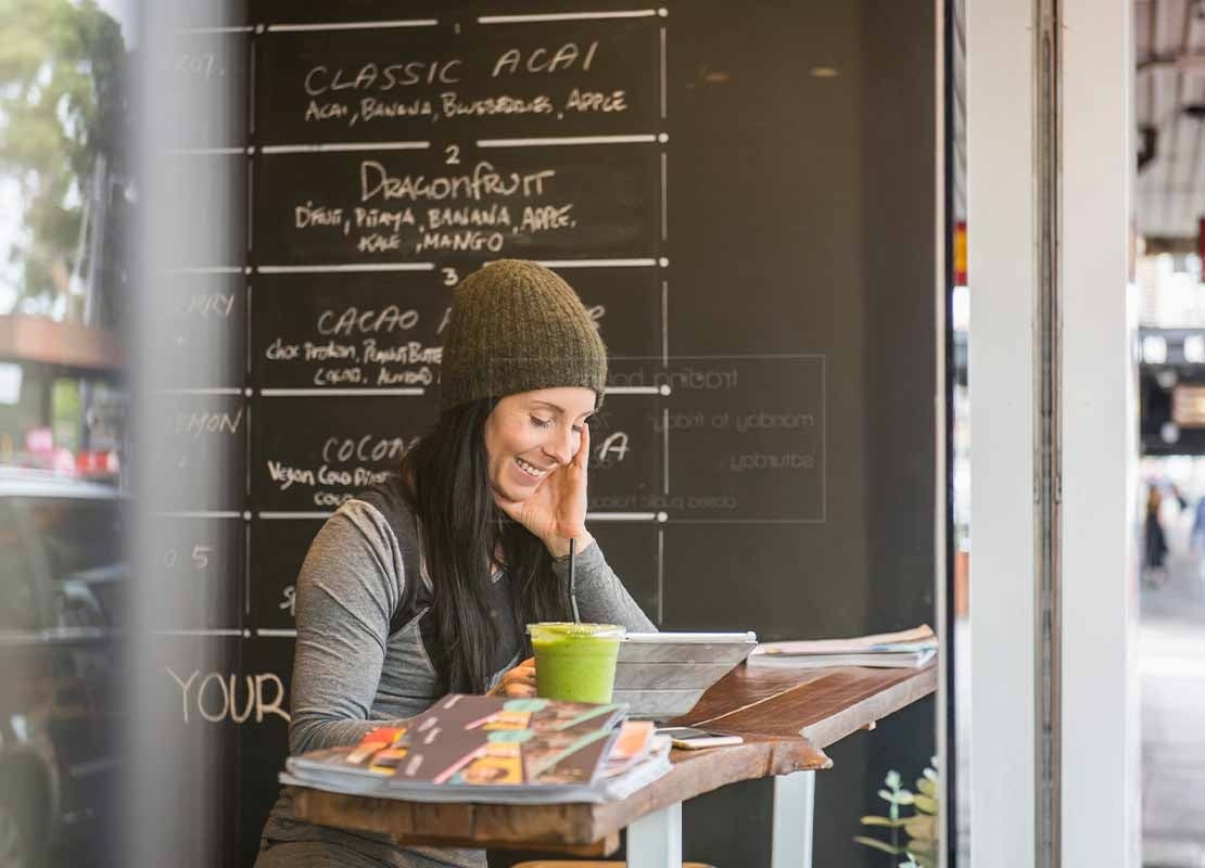 Cliente feliz sentada en la mesa de un negocio de food service revisa en una Tablet el menú de restaurante digitalizado