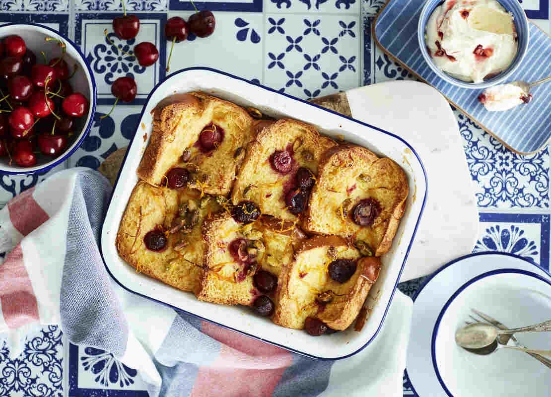 Bandeja de aluminio con 6 torrejas decoradas con fruta y manteca y alrededor una taza con cerezas y otra con helado