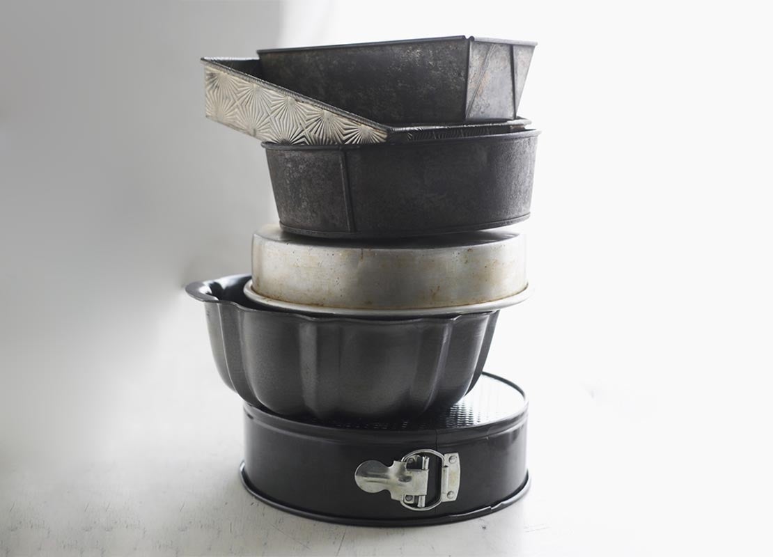 Pila de moldes para tartas en seis diferentes tamaños, diseños y acabados, que son utensilios básicos de repostería