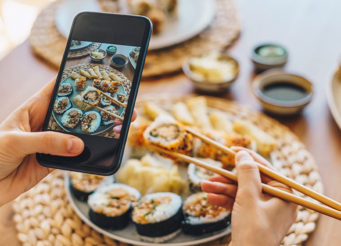 Persona toma foto a un plato de sushi para subir a sus redes sociales y aportar a un plan de marketing gastronómico