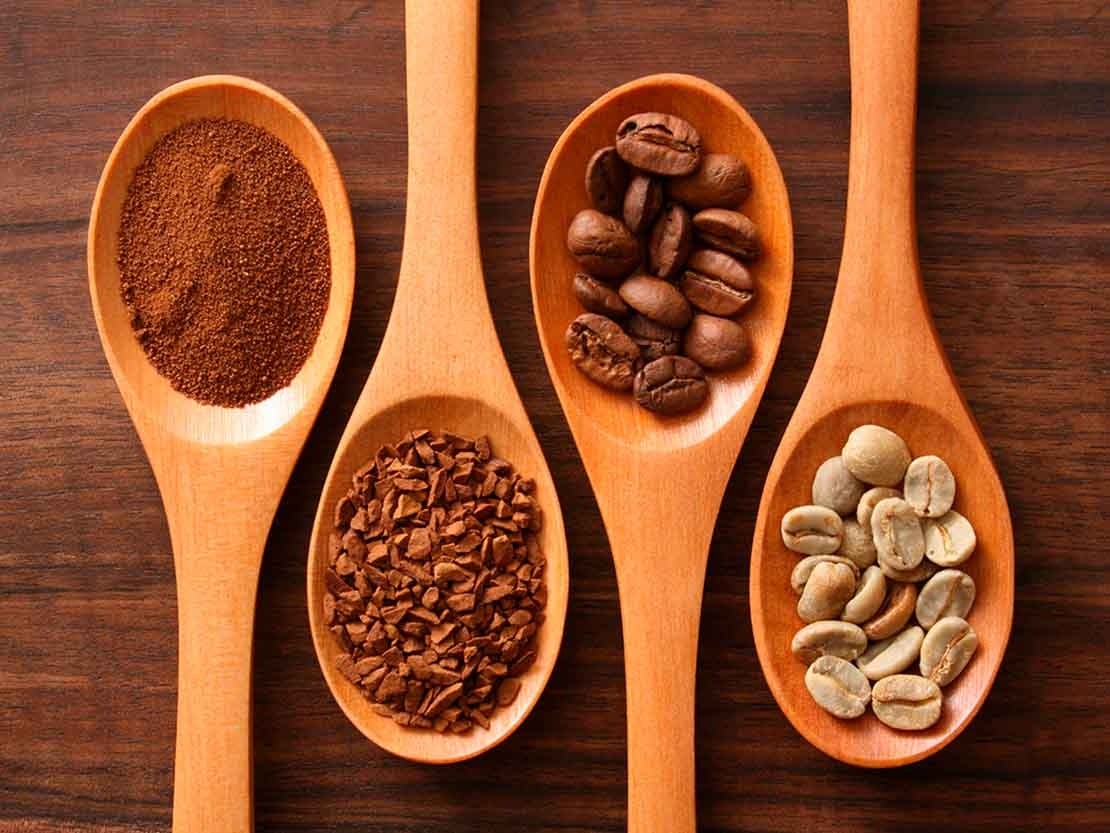 Cuatro cucharas de madera cada una con café soluble, tostado y molido, grano tueste oscuro y claro de NESCAFÉ®