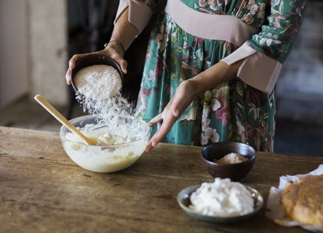Manos de mujer vierten harina en un bowl de vidrio sobre una mesa en un negocio de Street food