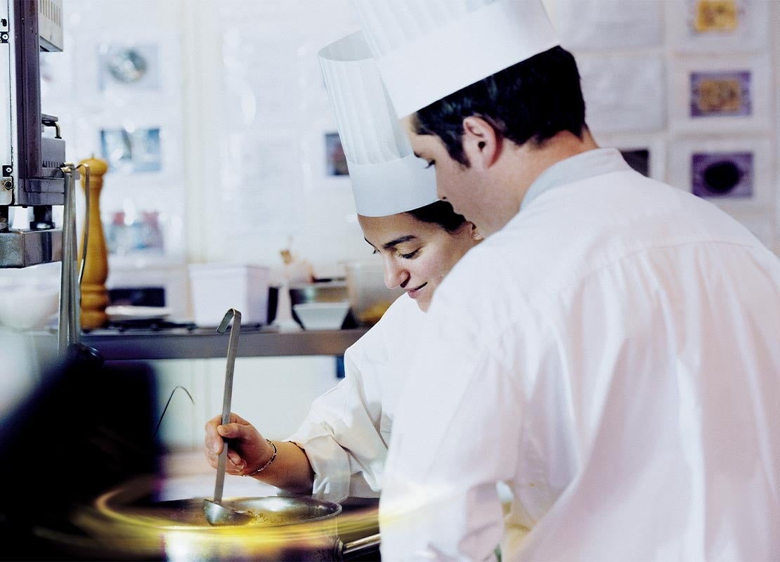 Dos jóvenes chefs del Programa YOCUTA revisan sus preparaciones en una olla