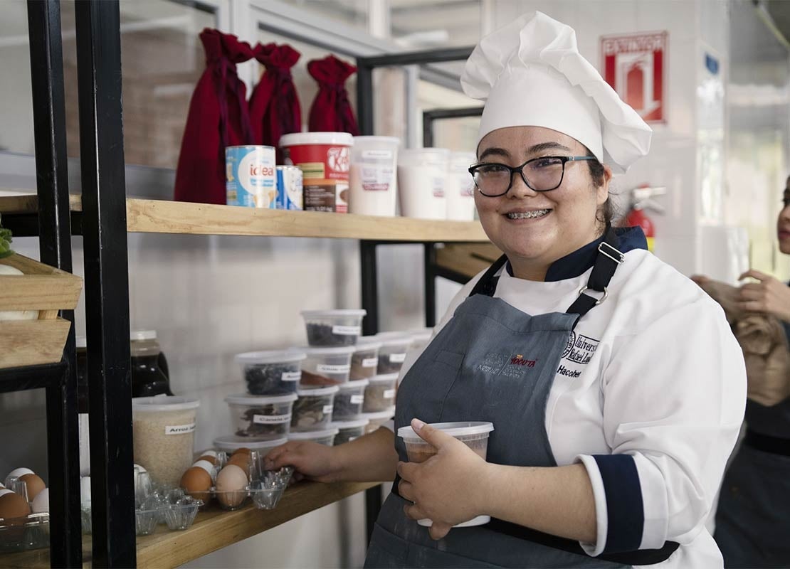 Joven chef del Programa YOCUTA elige algunos ingredientes de las estanterías de una cocina comercial