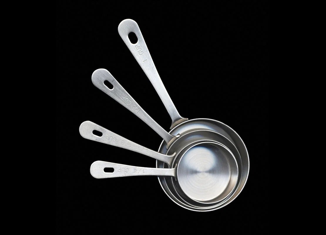 Utensilios de cocina esenciales como estas cuatro tazas medidoras de acero inoxidable colocadas una entre otra