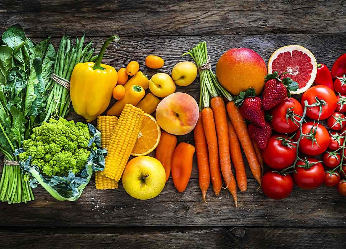 Frutas y verduras limpias ordenadas por colores en una mesa de madera, luego de ser desinfectadas