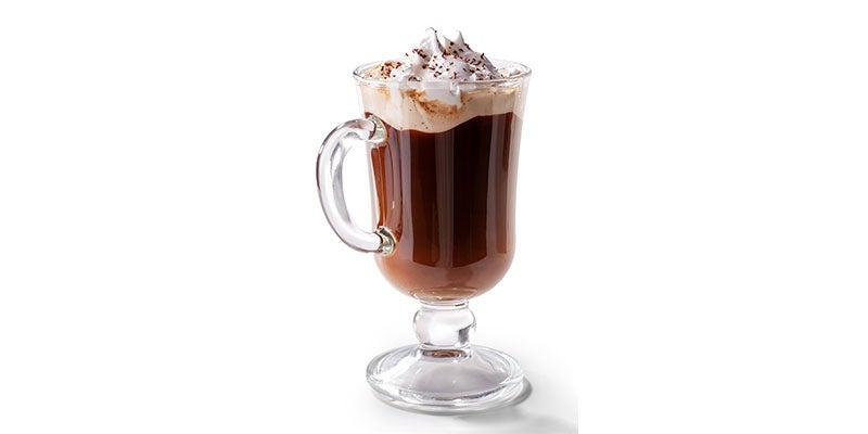 Café mocha servido en un vaso alto de cristal y decorado con crema