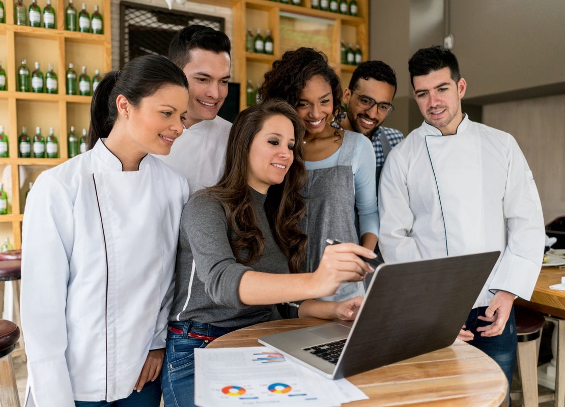 Equipo de trabajo de un bar observa en una laptop estrategias de reducción de costos