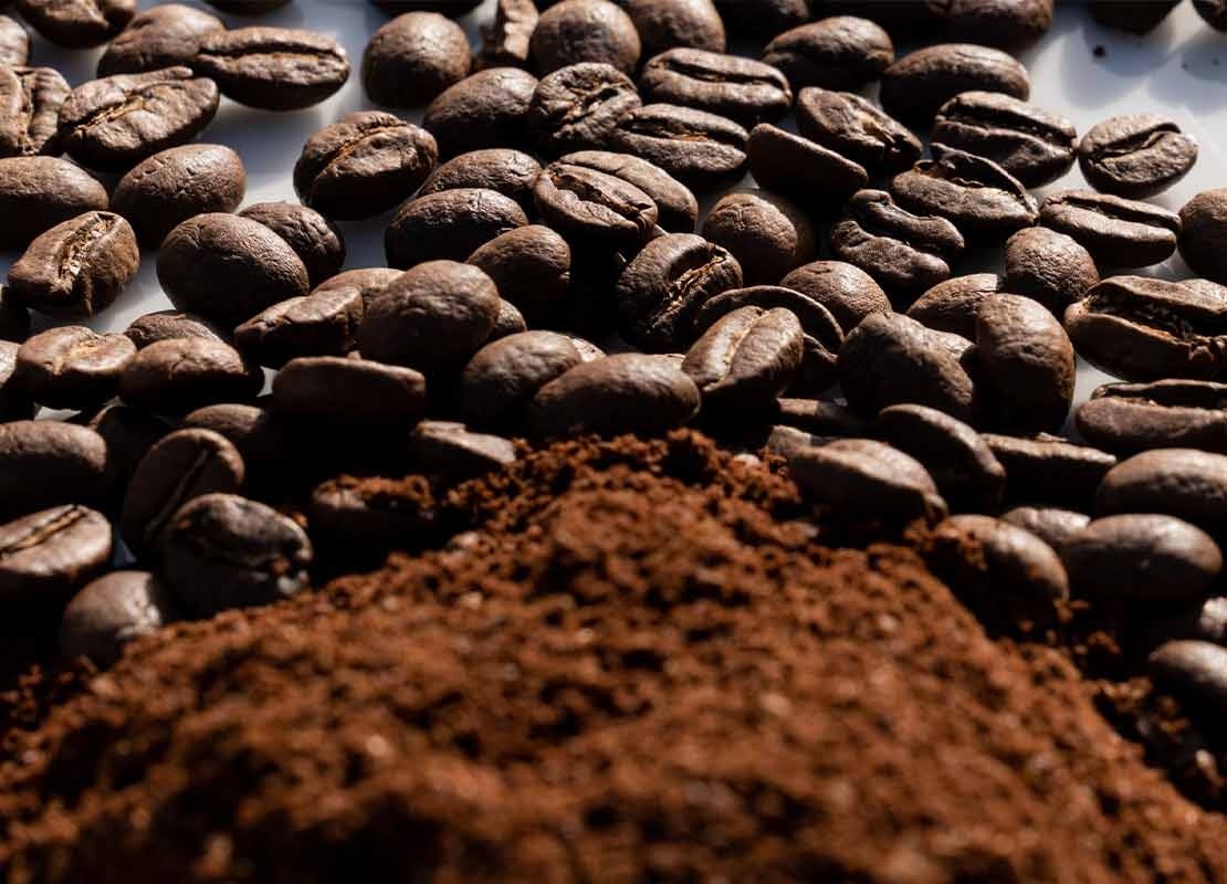 Sobre una mesa, café en grano y molido procesado por molinos de café
