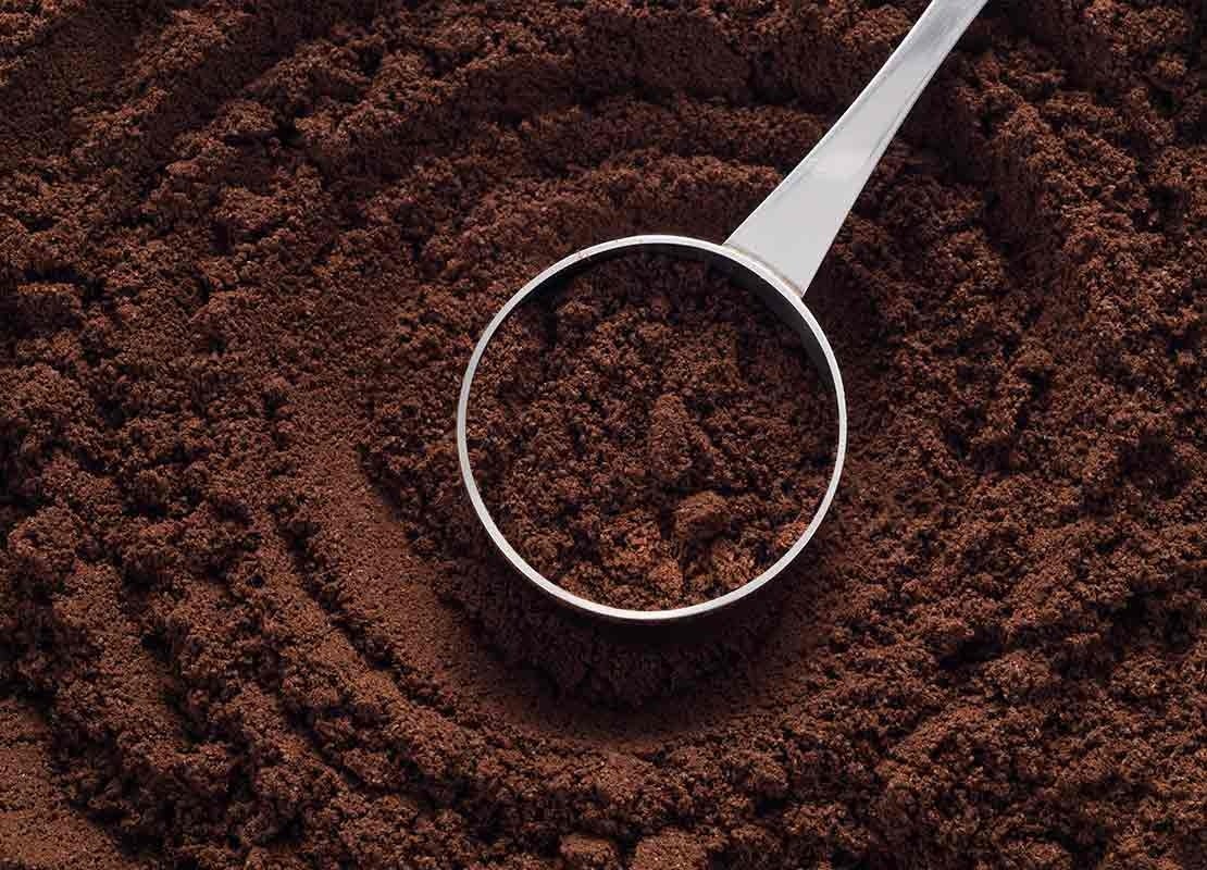 Café molido en cucharilla medidora de acero inoxidable